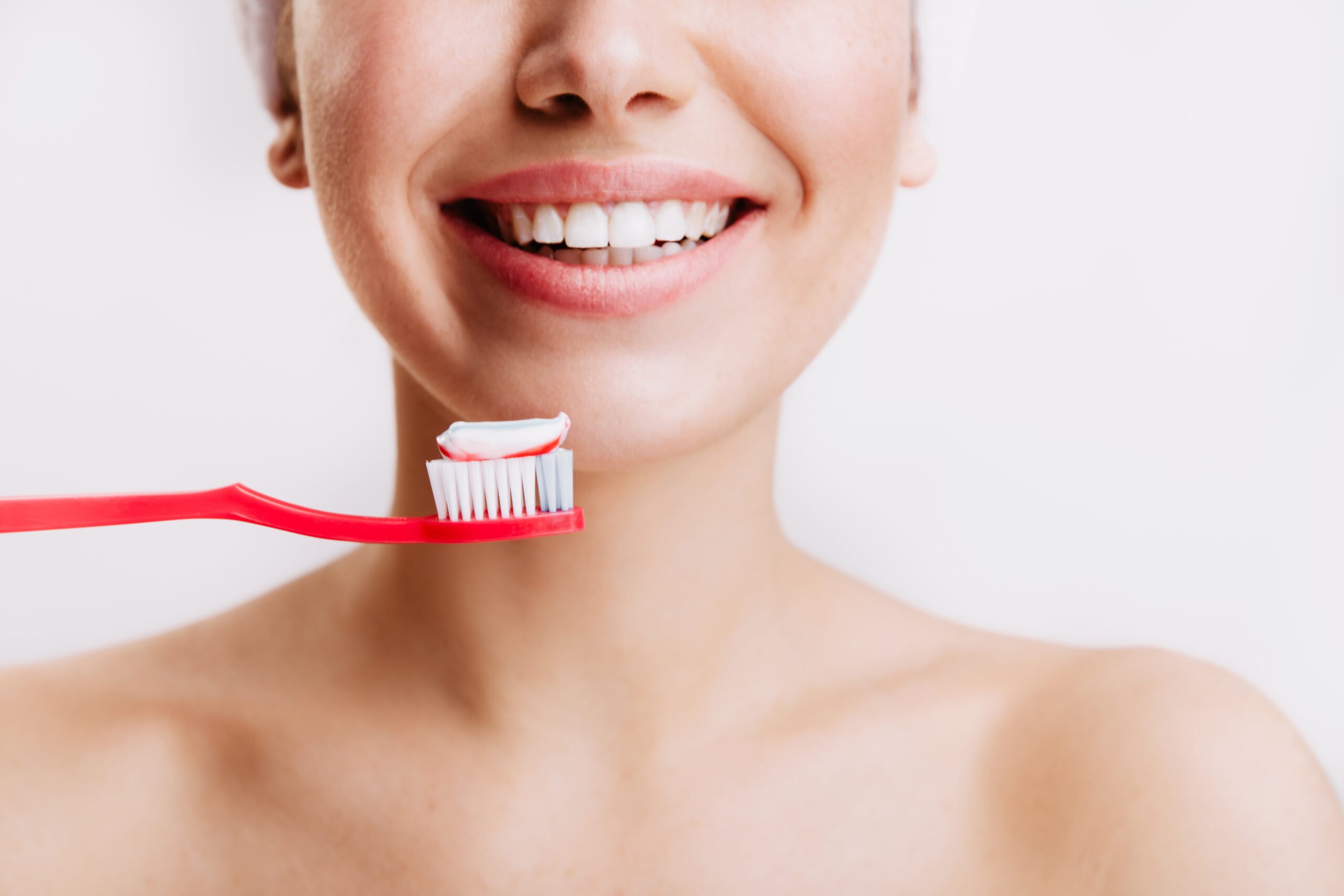 teeth whitening facts - woman with nice teeth holding a toothbrush.